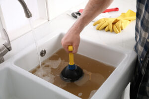 person using a plunger to unclog a dirty sink