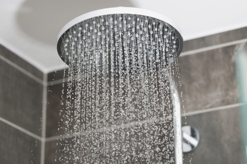 Close-up Of Water Running From Shower Head And Faucet In Modern